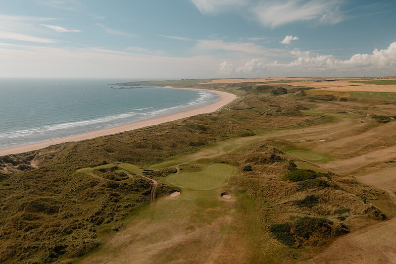 Dune fairways and bunkers bordering a long sandy beach and the sea