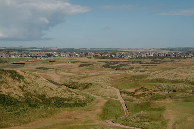 A links course of mounded dunes stretching towards a distant town