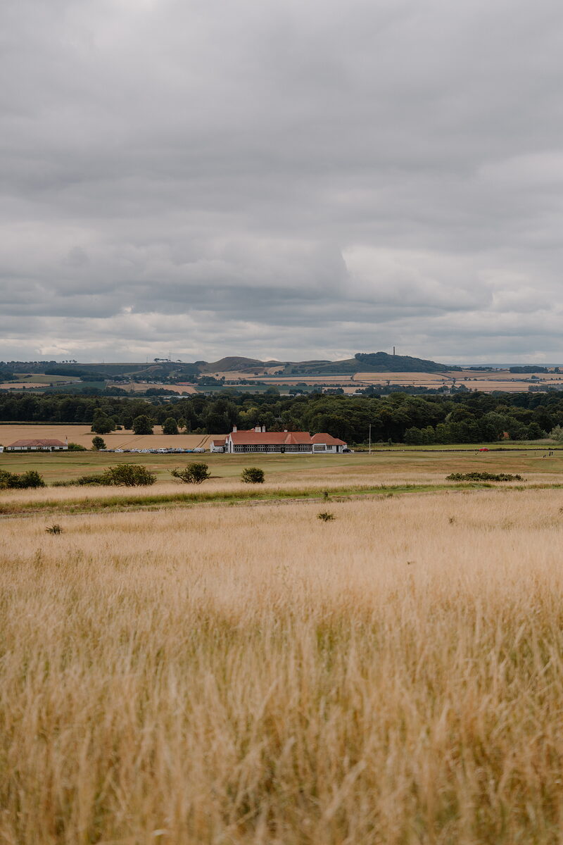 Farmland and a distant hamlet stretching towards low hills under a heavy sky.