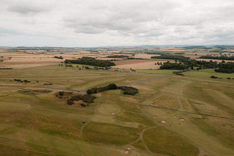 A fairway crossed by paths, farmland and woodland stretching to the horizon