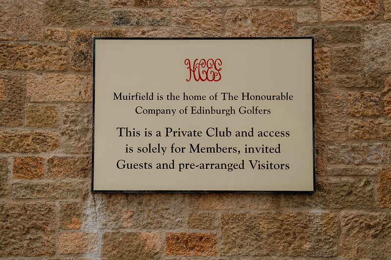 A plaque reading Muirfield is the home of The Honourable Company of Edinburgh Golfers, mounted on a stone wall