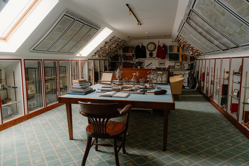 A heritage room at Nairn displaying old golf clubs, blazers and trophies in glass cabinets around a central table