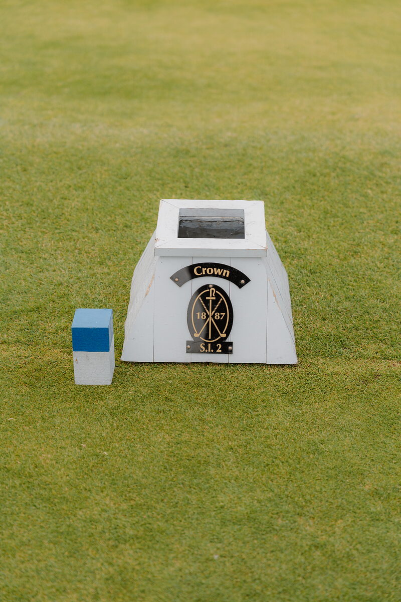 A small marker box on the green reading Crown, beside a distance post