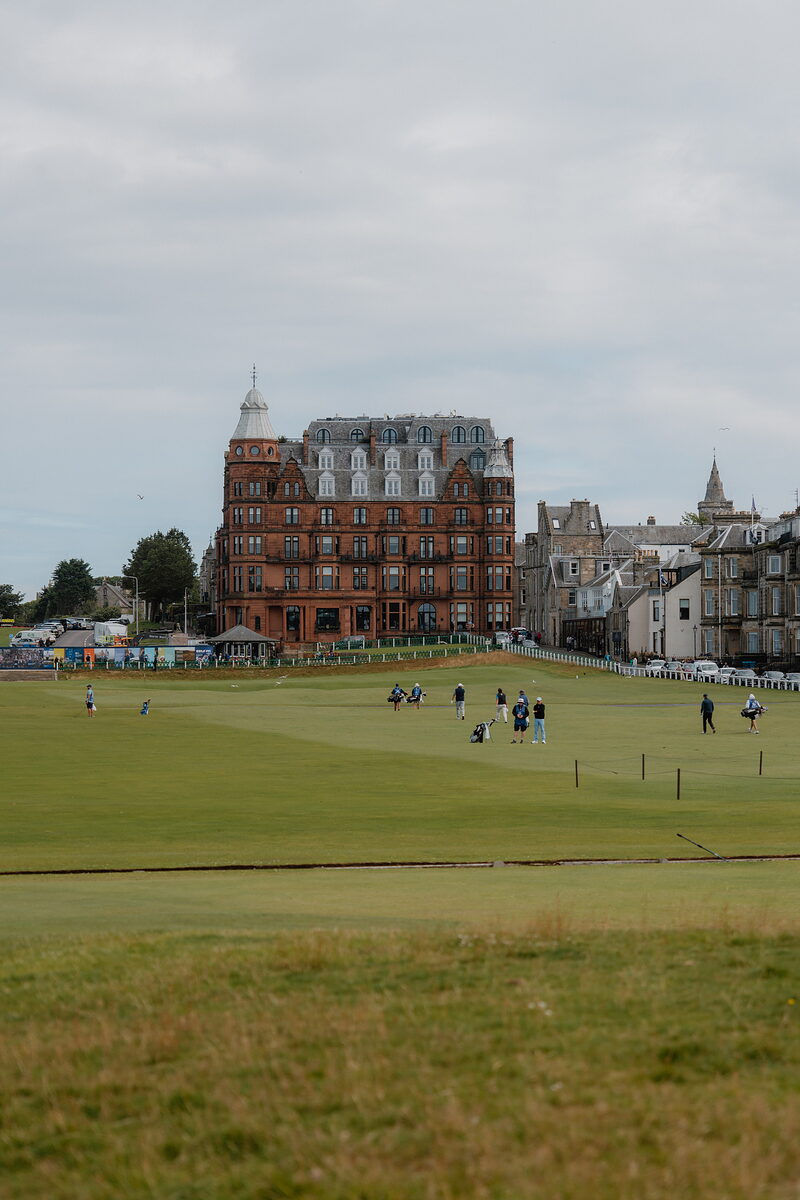 Golfers finishing at St Andrews Links, the red sandstone Rusacks Hotel rising behind the 18th green.
