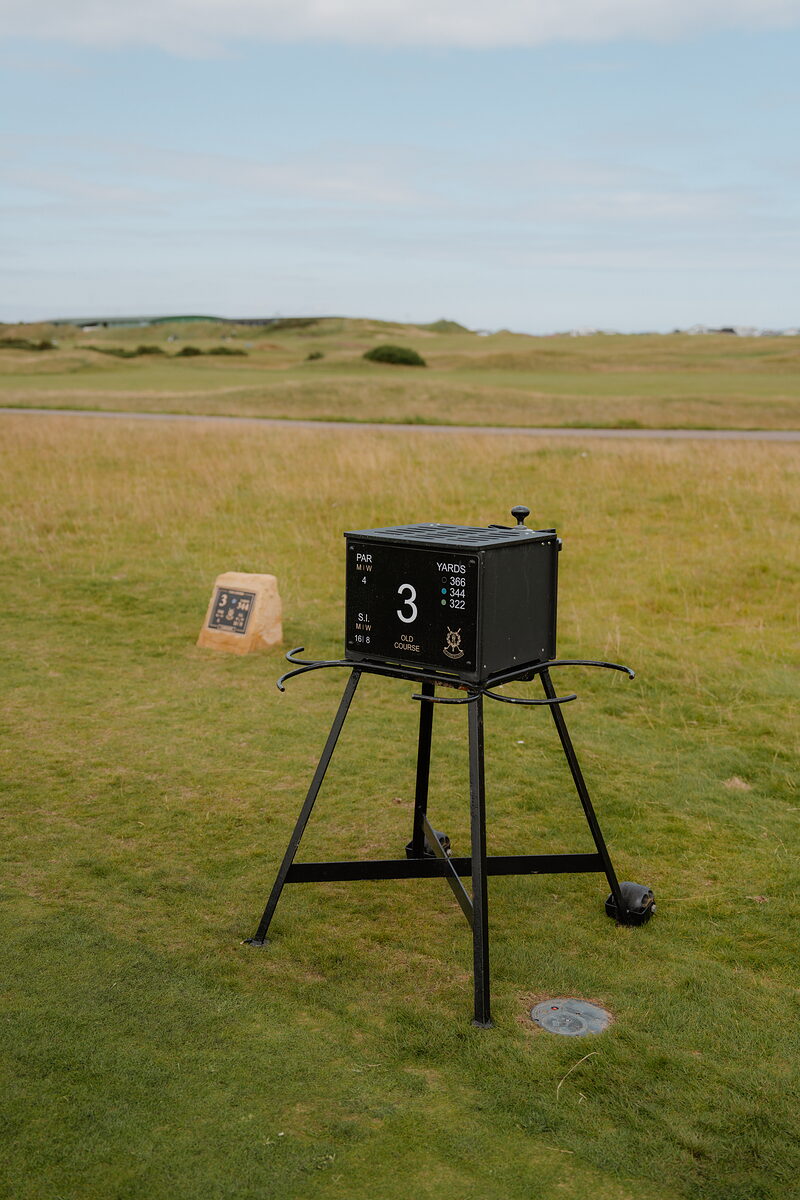 A hole-marker box gives the par and yardage for the Old Course's third hole, a stone plaque beside it.