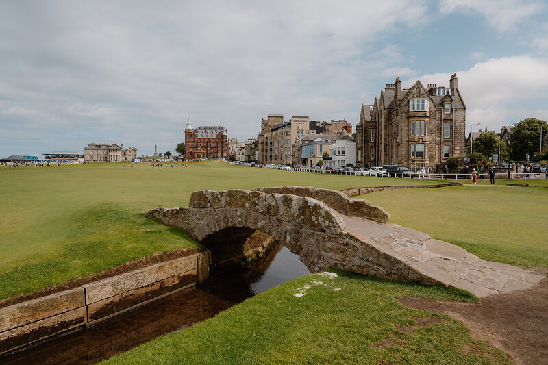 The Swilcan Bridge arches over its burn on the Old Course, the town rising behind.