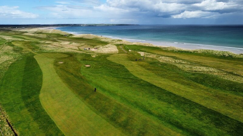 Wick’s links from the air, striped fairways and pale dunes running beside the long beach of Sinclair Bay.