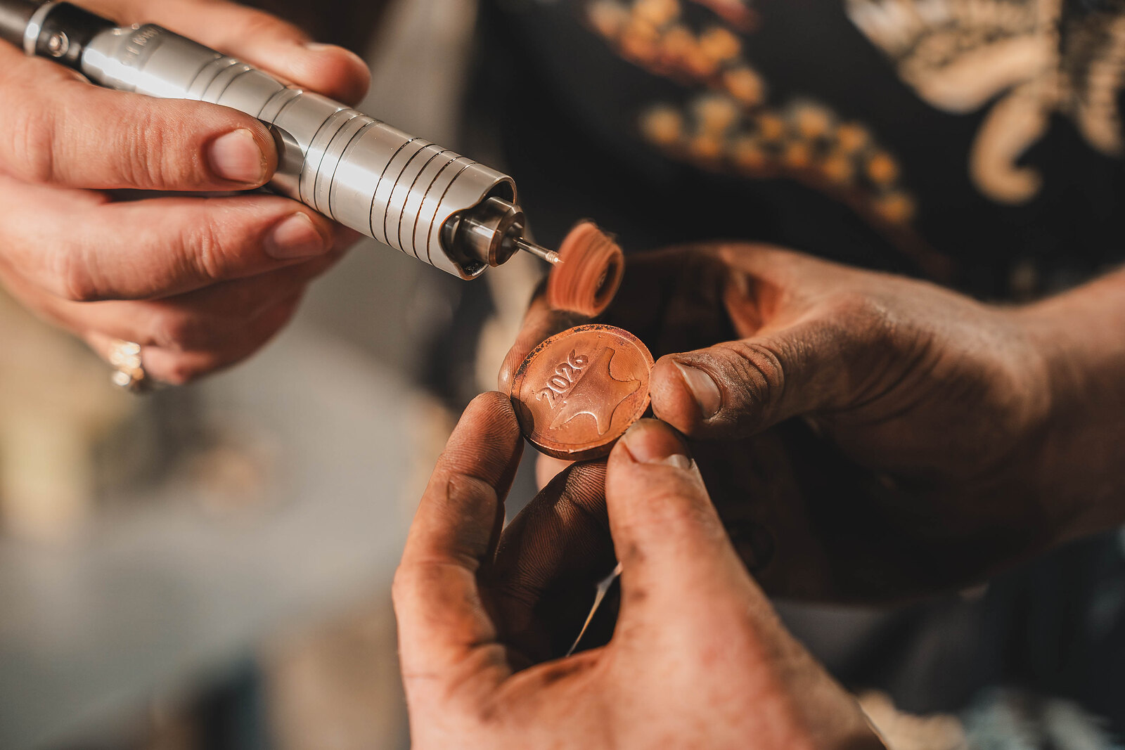A freshly struck copper coin held up between finger and thumb, its design pressed into the metal.