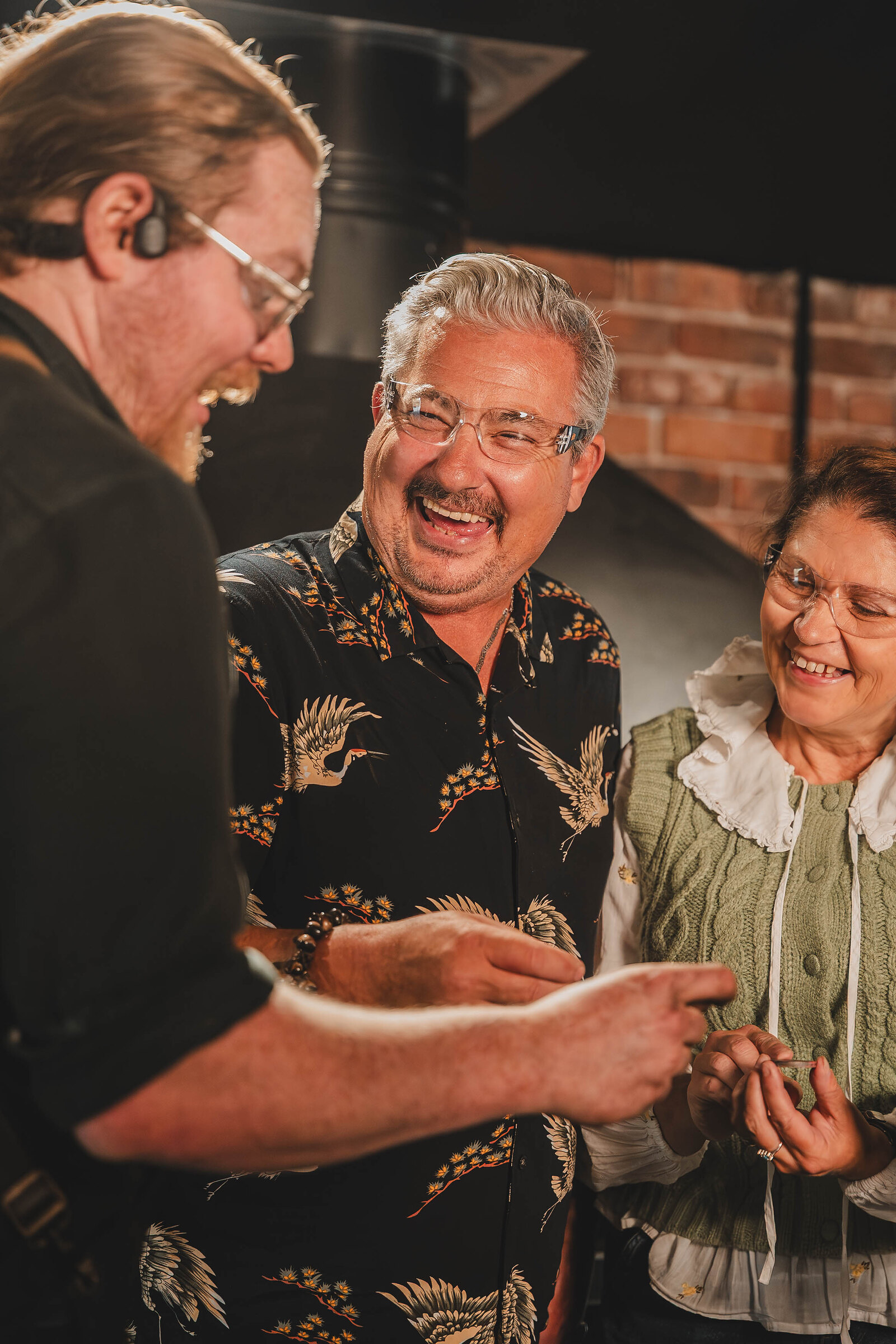 Two visitors laugh as the blacksmith shows them their finished coin.
