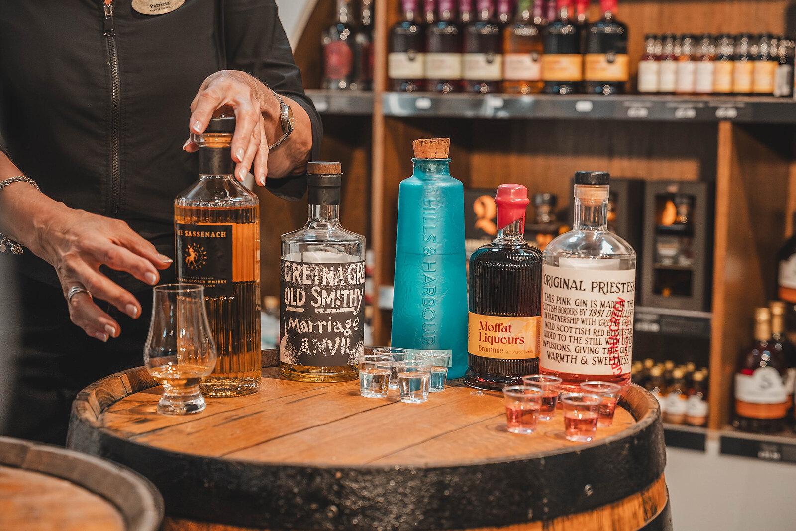 Bottles of local whisky and gin lined up on a barrel top, tasting glasses poured in front of them.