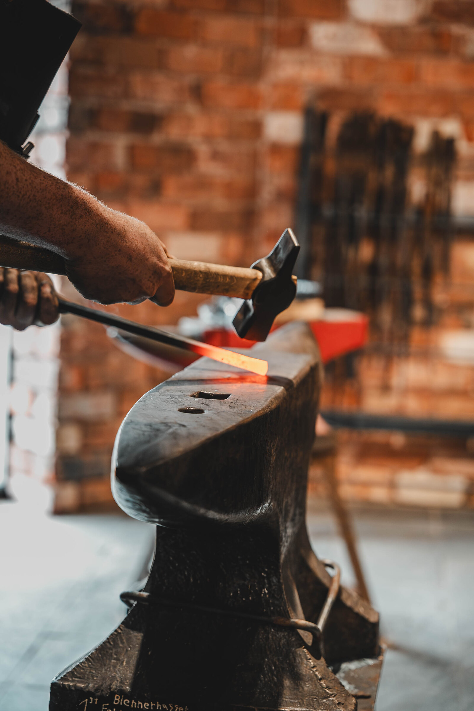 Sparks of heat in a glowing steel bar held to the anvil's horn.