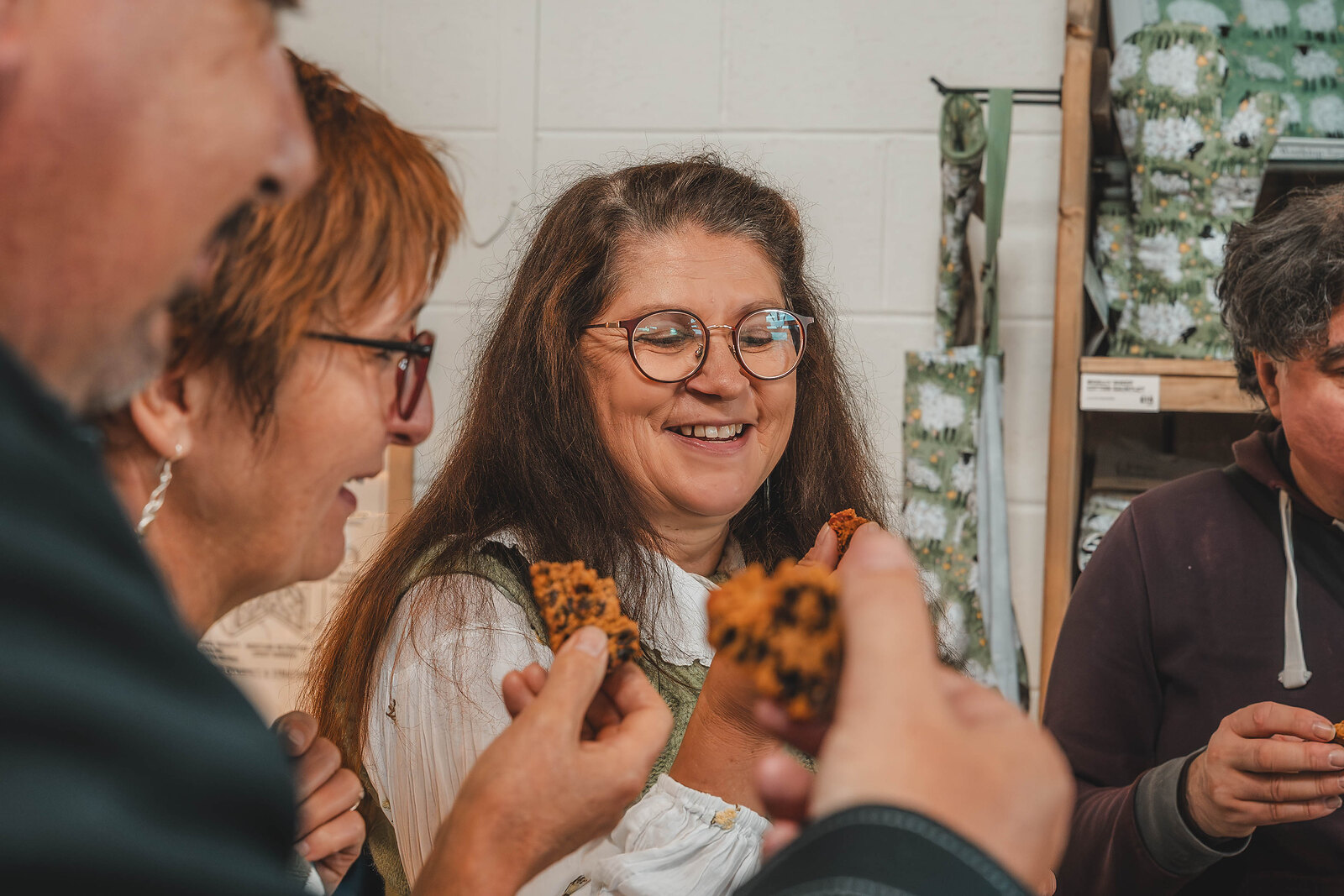 Two women smile as they try pieces of tablet and biscuit.
