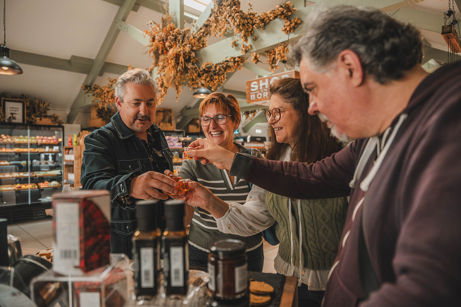 Visitors reach for samples at the First Taste of Scotland, jars and sauces on the counter in front of them.