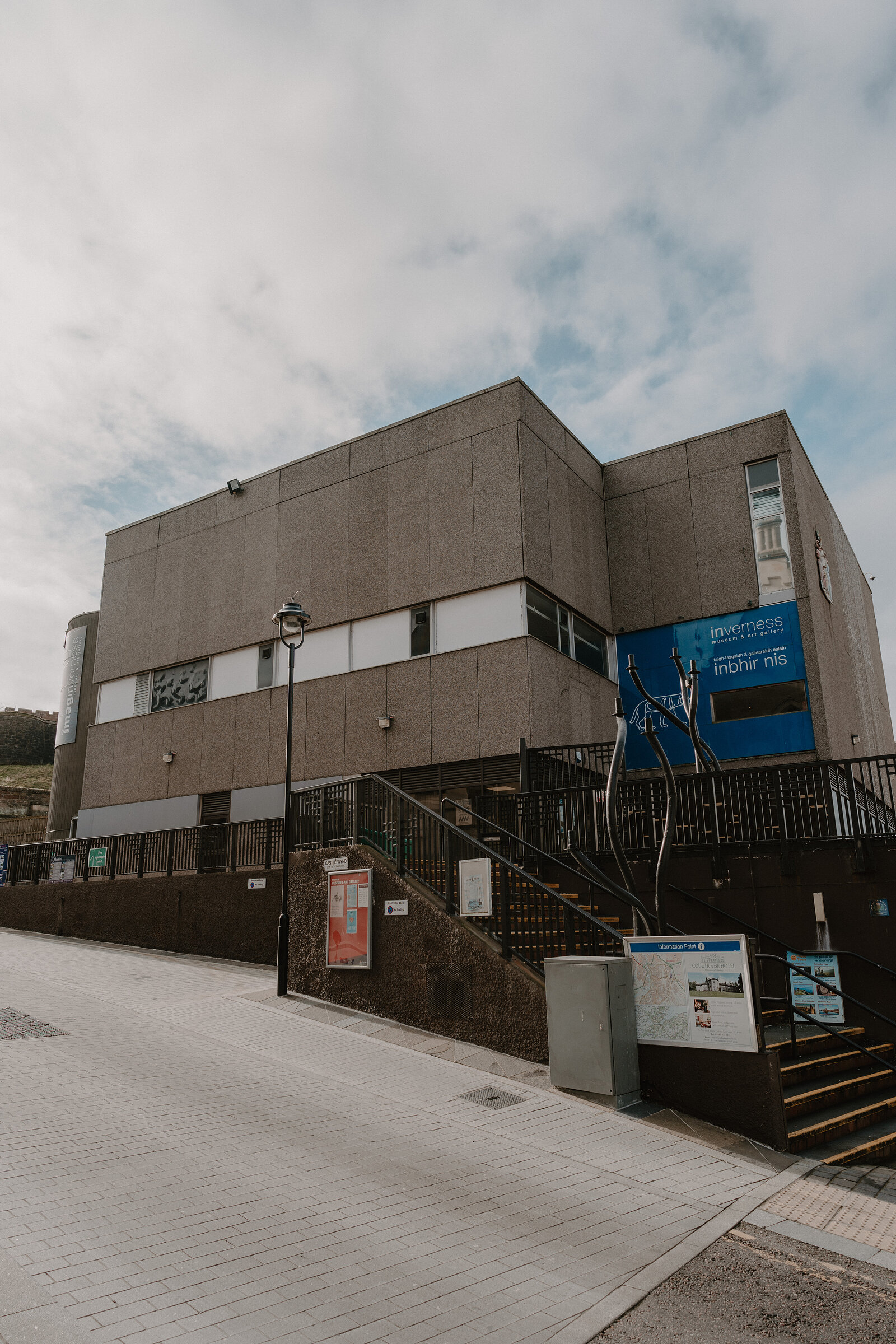 A concrete museum building carries a sign reading 'Inverness, Inbhir Nis', a staircase and information panels leading up to the entrance.