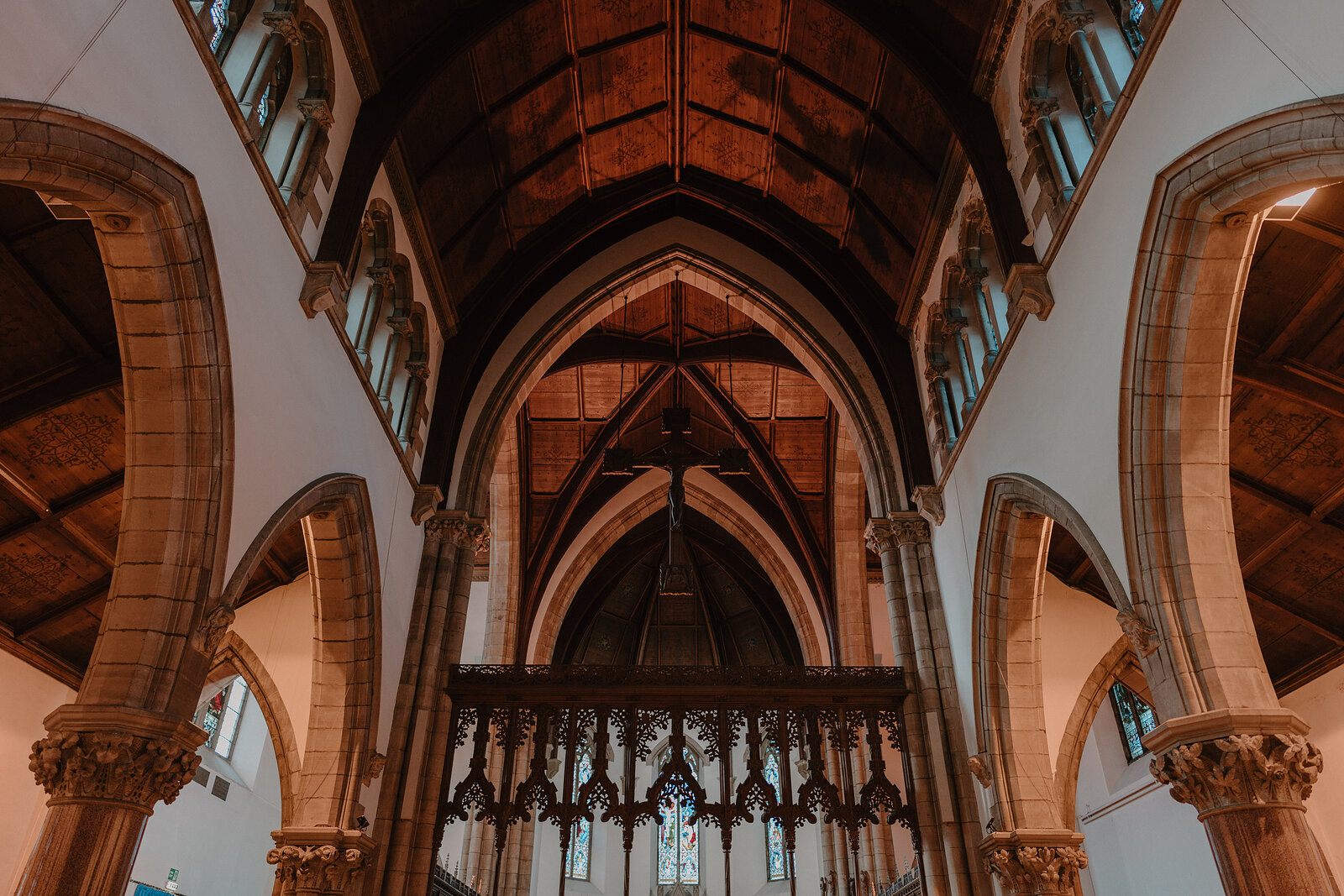 A vaulted timber ceiling with carved stone ribs rises above a wooden rood screen dividing the nave from the chancel.