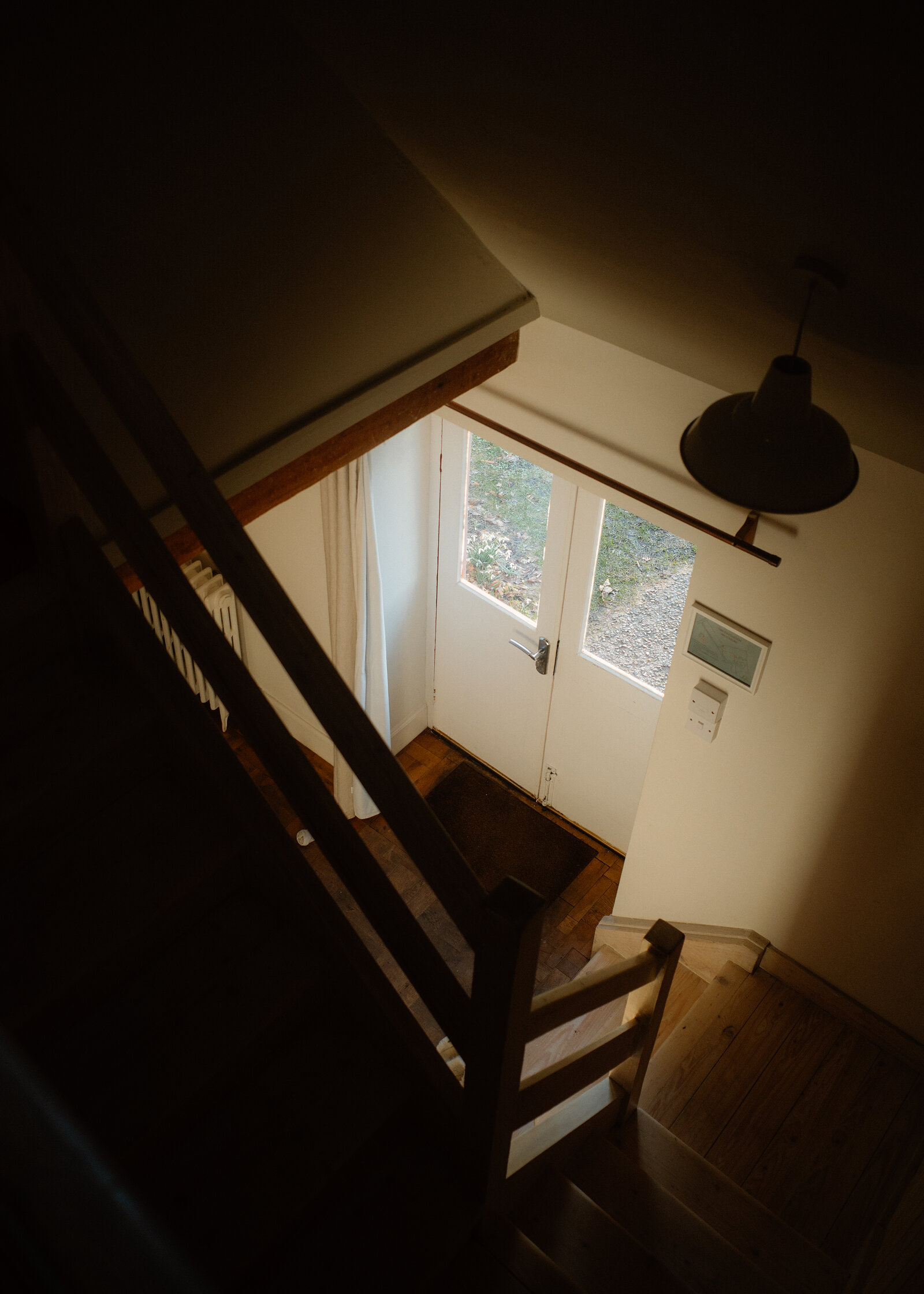 Looking down a timber staircase to a glazed front door.