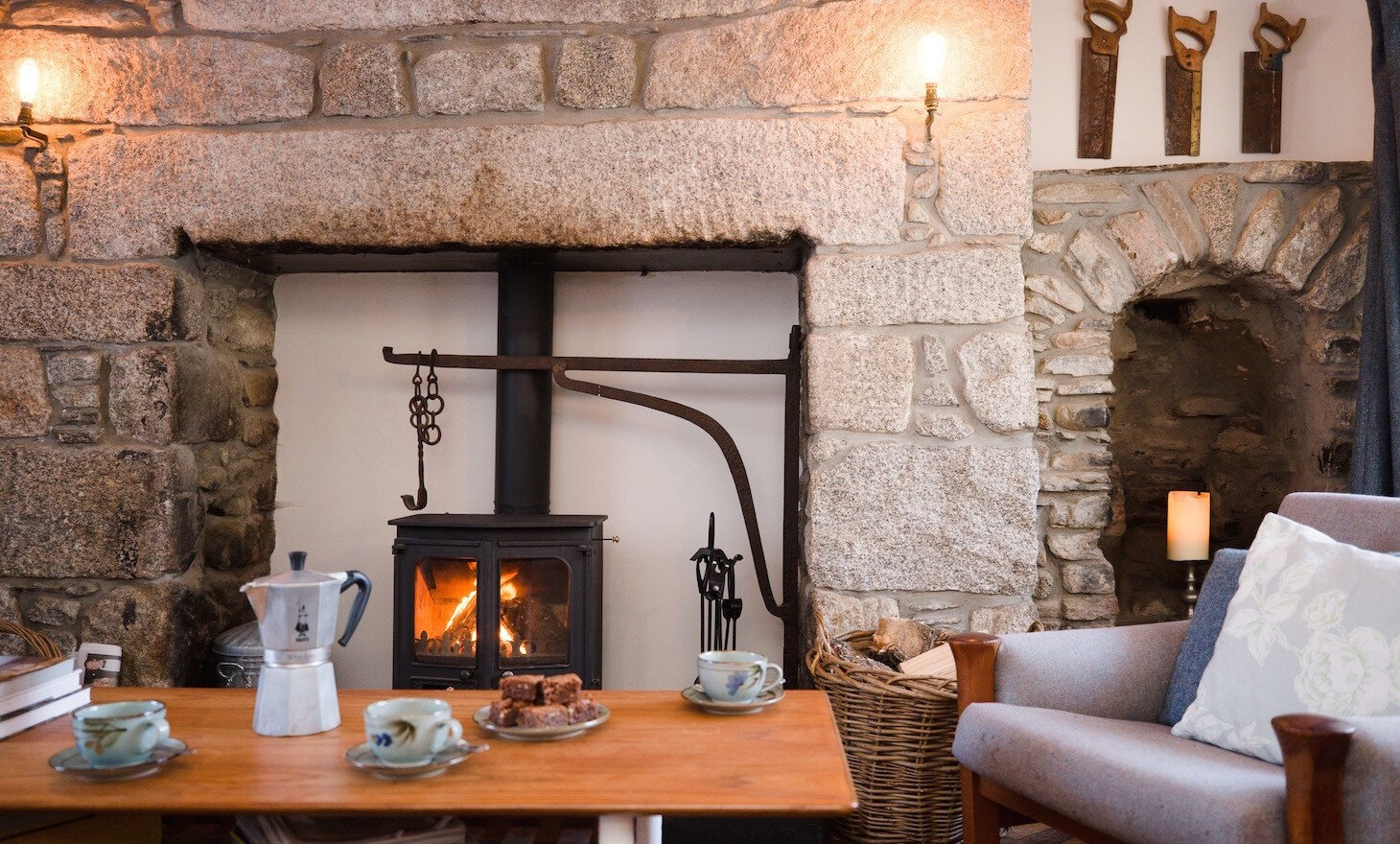 The great granite surround of the old range, now holding a lit stove, with a coffee pot and cups on the table in front.