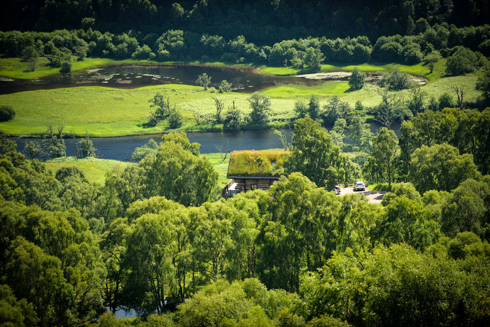 Looking down on the green glen, the River Glass and a turf-roofed cabin among the birches.