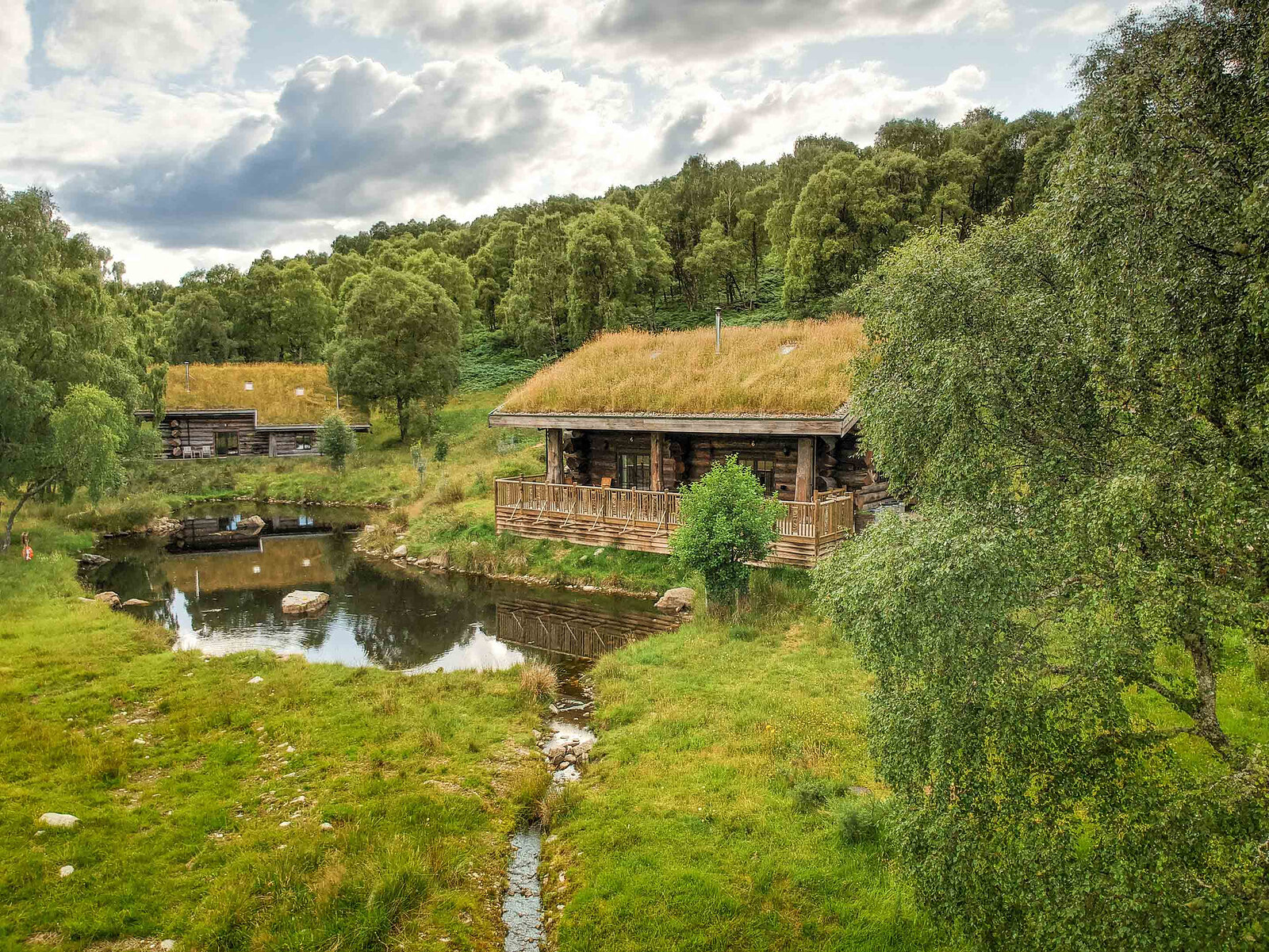 From above, two turf-roofed cabins by the duck pond, a burn running down through the green grass.
