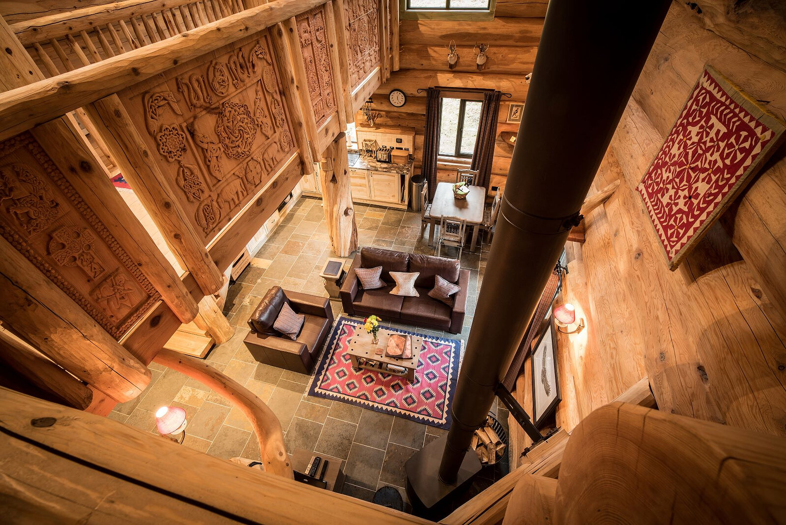 Down past the stove pipe from Certhia's carved gallery to the leather sofas on a red rug below.