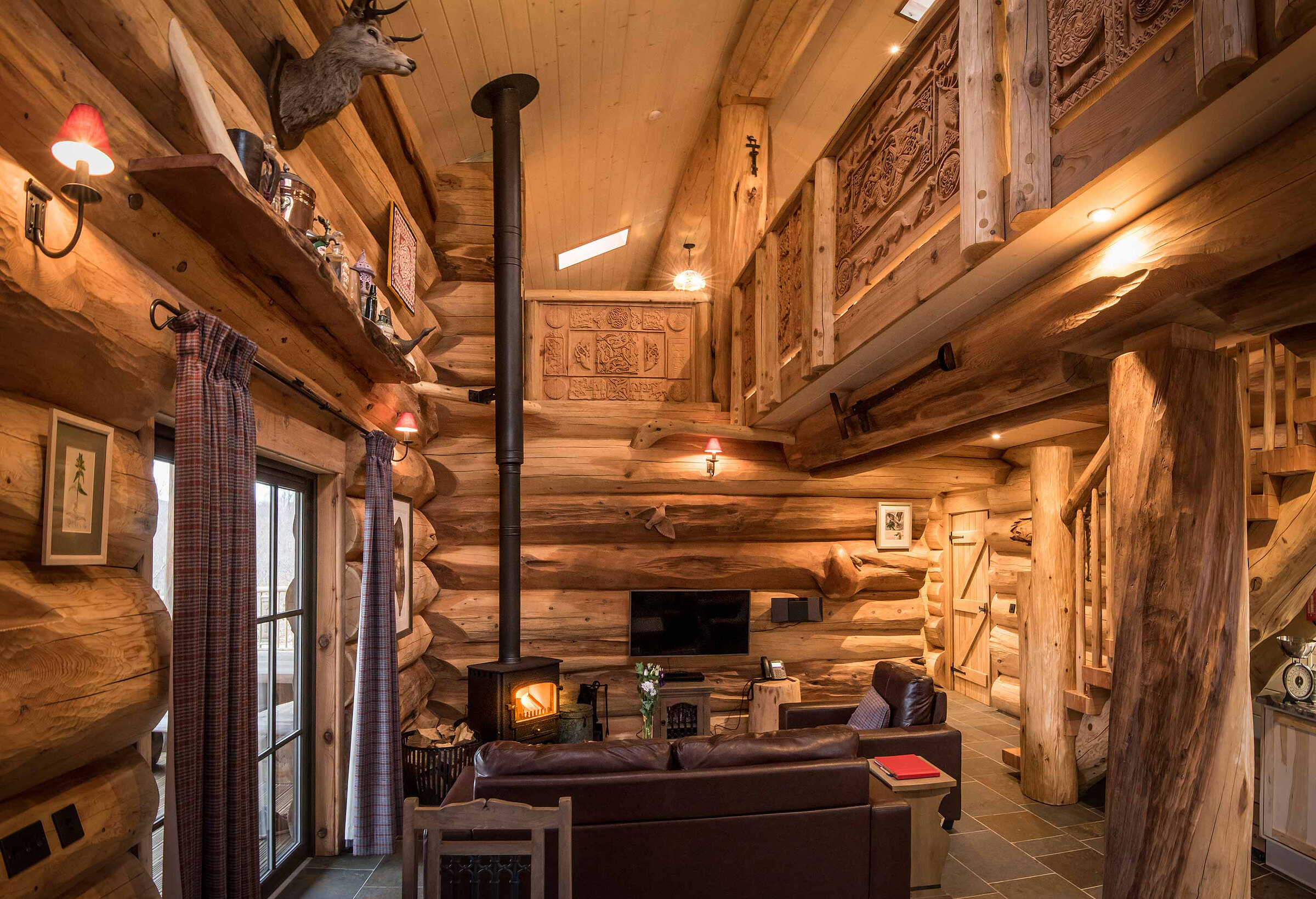 Cinclus's living room under the carved gallery, the stove lit below a stag's head and shelves of old jugs.