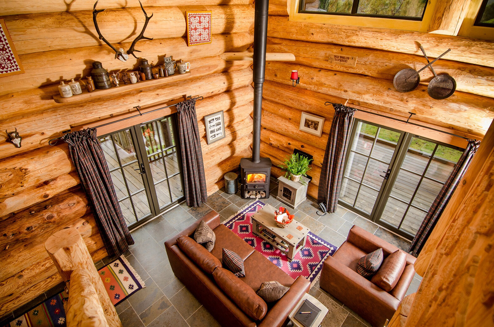 From the gallery down into Strix's living room: leather sofas on a red rug, the stove between two glass doors.