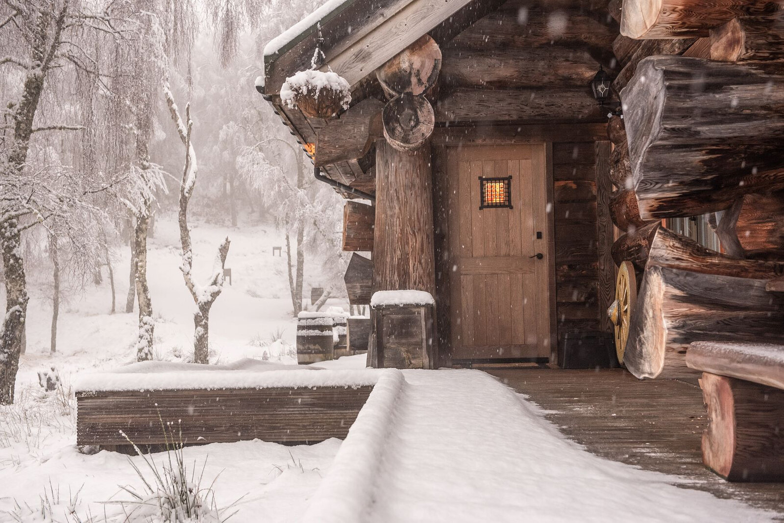 Sylvia's oak door and log corner in the snow, snow falling on the birches.