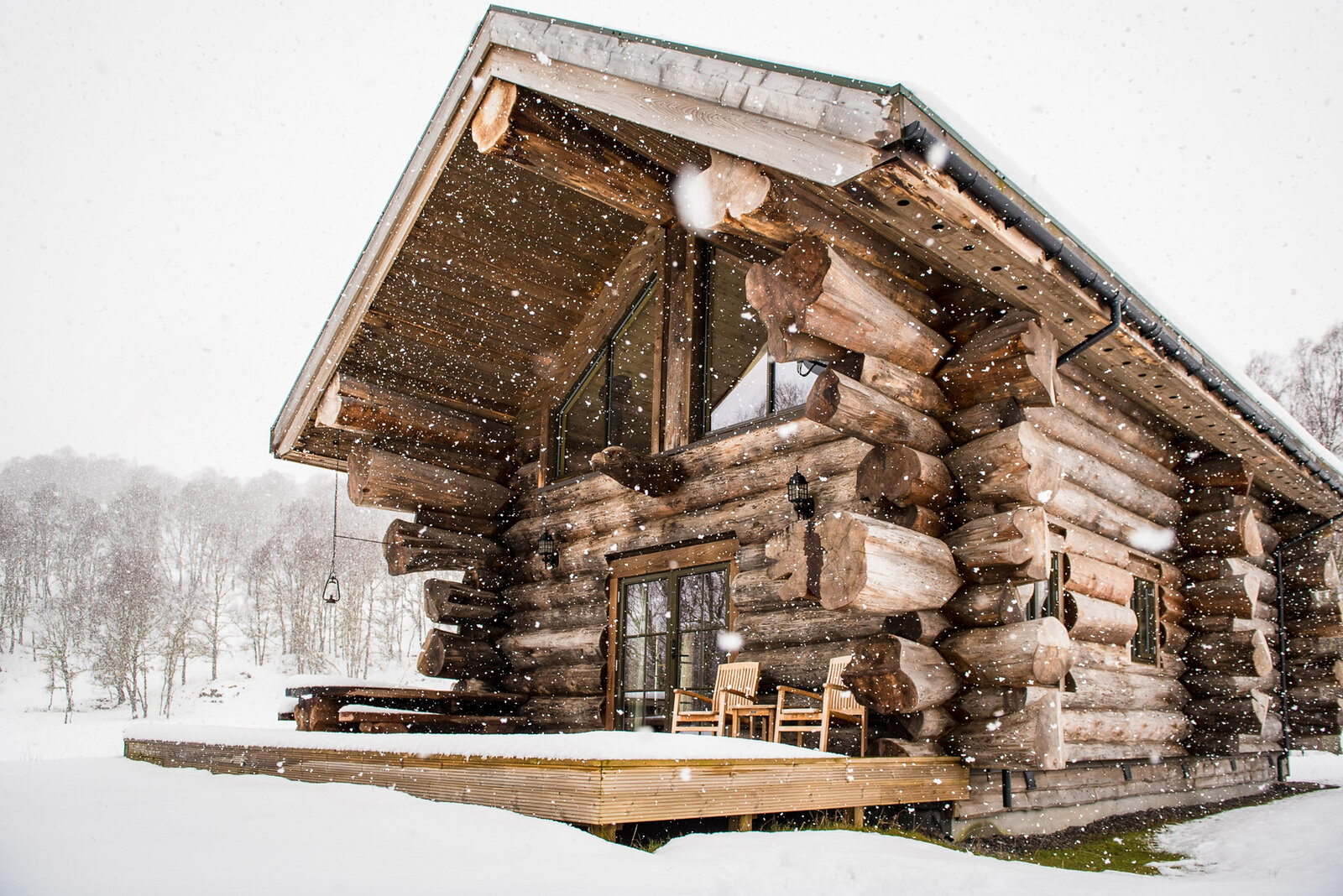 Sylvia's gable and deck in falling snow, chairs out on the boards.