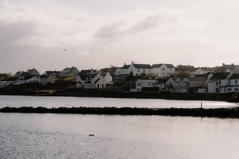 A row of whitewashed houses lines a curving bay.