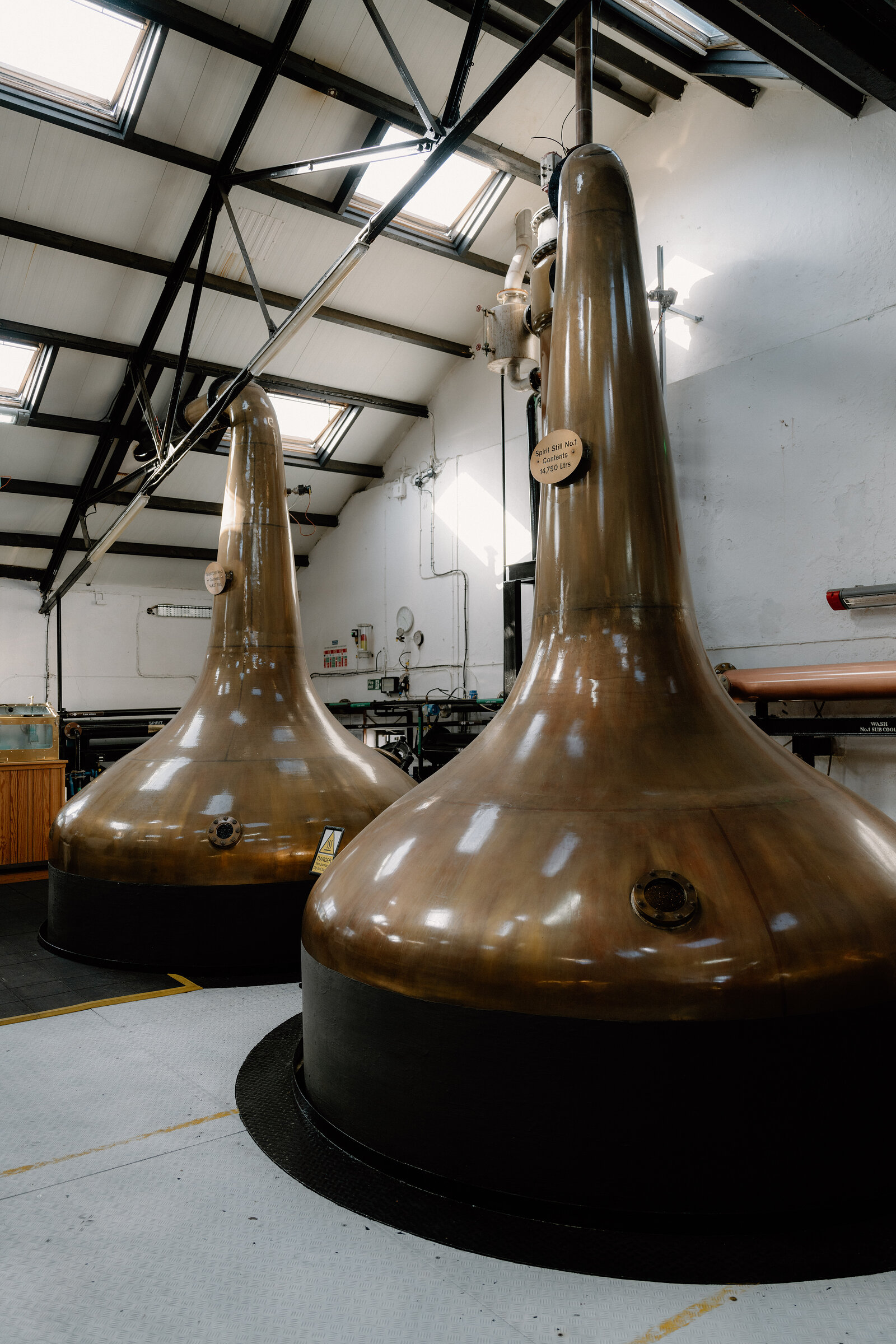 Copper stills in the Bowmore still house, in black and white.