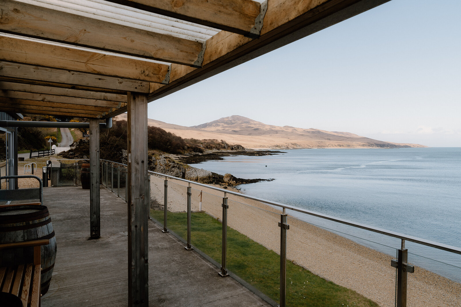 A wooden pergola frames a terrace view of the sea and distant mountains.