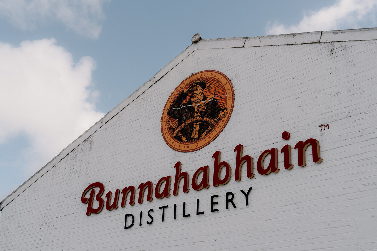 A painted roundel and lettering spell out "Bunnahabhain Distillery" on a gable wall.