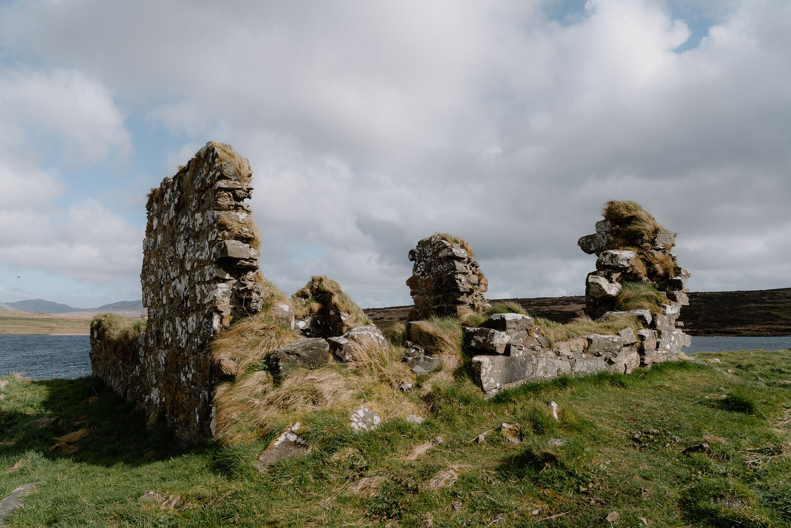 The ruined stone walls of a chapel stand beside a loch at Finlaggan.