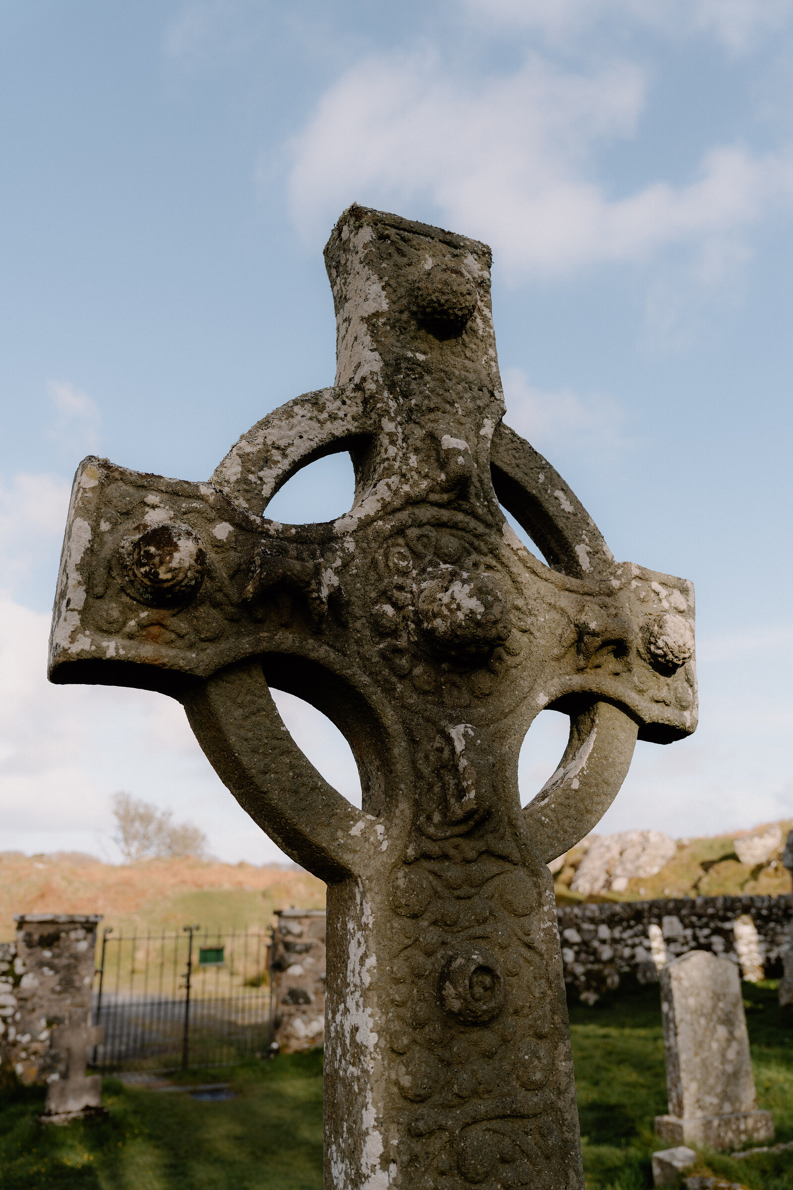 A close-up shows the lichen-covered carving on the ringed head of a stone cross.