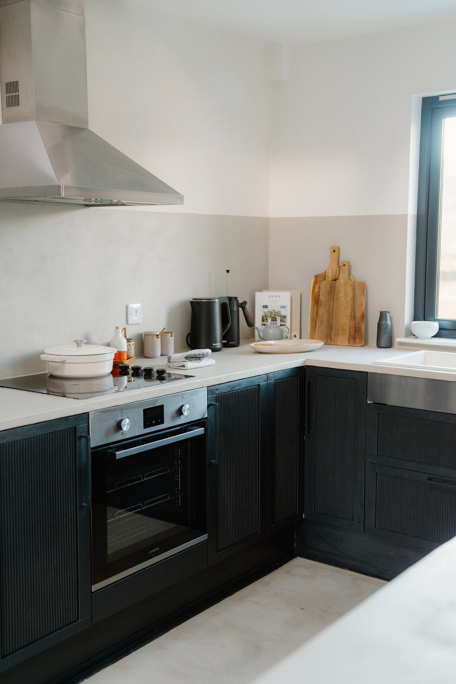 Wooden chopping boards lean against the wall of a black-cabinet kitchen.