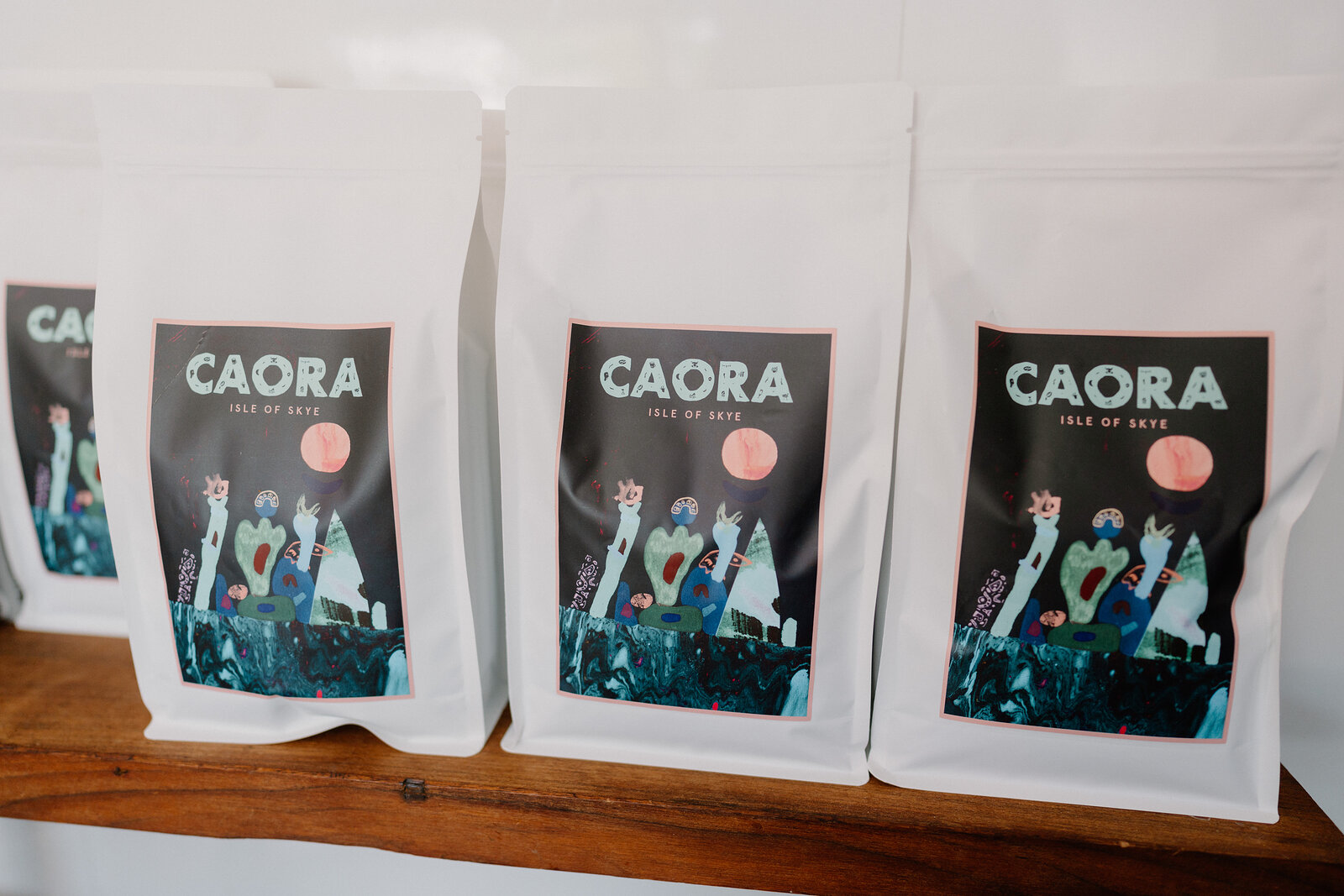 Bags branded 'Caora, Isle of Skye' are lined up on a wooden shelf.