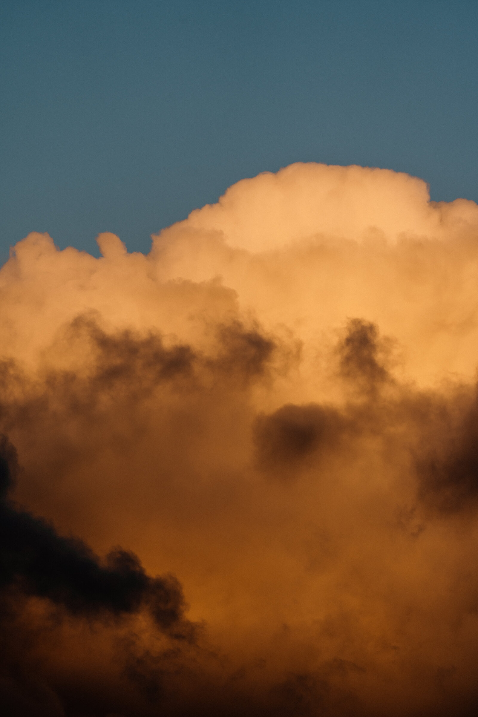 Golden light glows through billowing storm clouds at sunset.