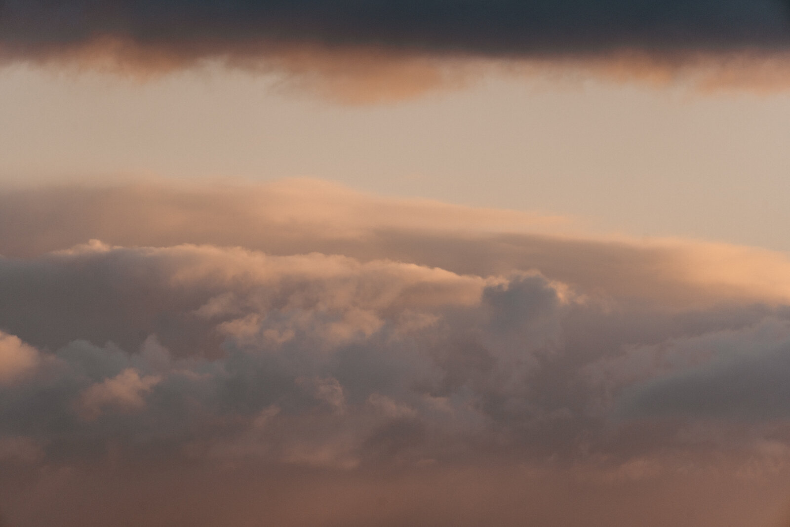 Layered clouds glow orange and grey at sunset over the sea.