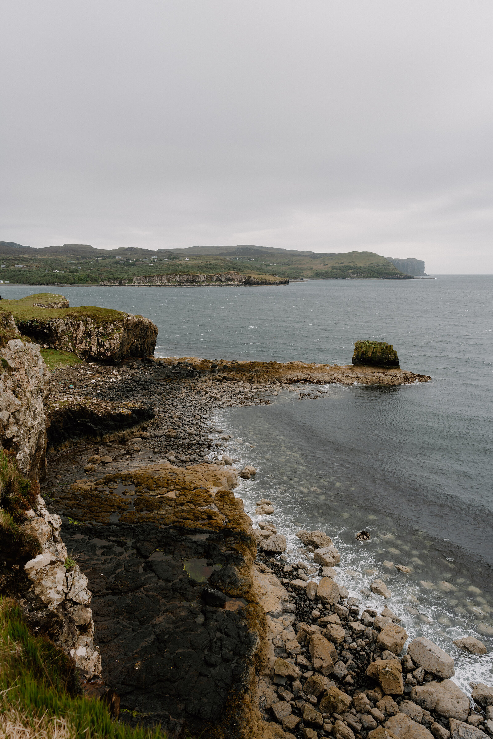 A rugged coastline of cliffs and a small sea stack meets the water on the Isle of Skye.