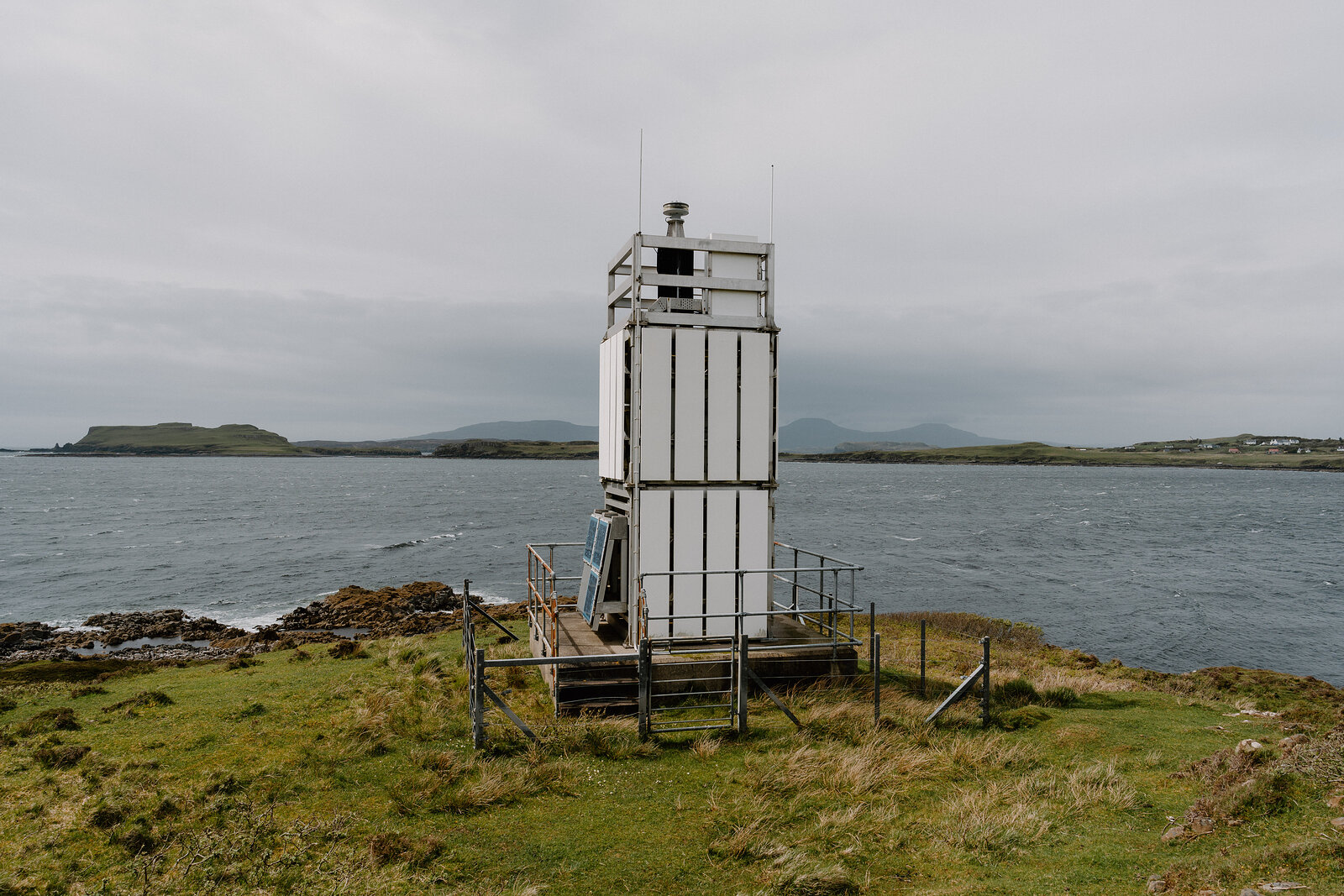 A white beacon tower stands on a rocky point on the Isle of Skye.