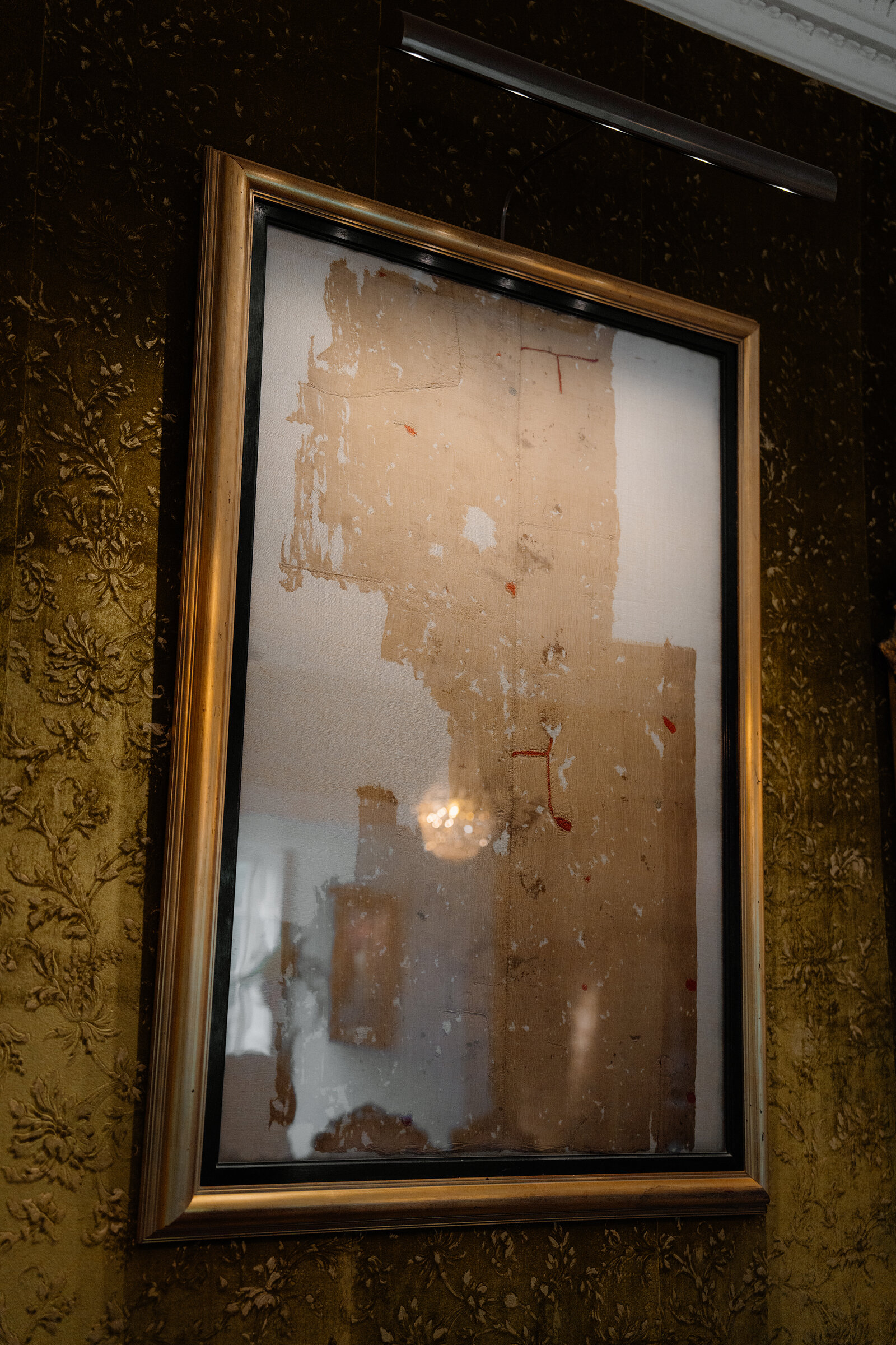 The tattered, ancient Fairy Flag of Dunvegan is displayed behind glass in a gilt frame.