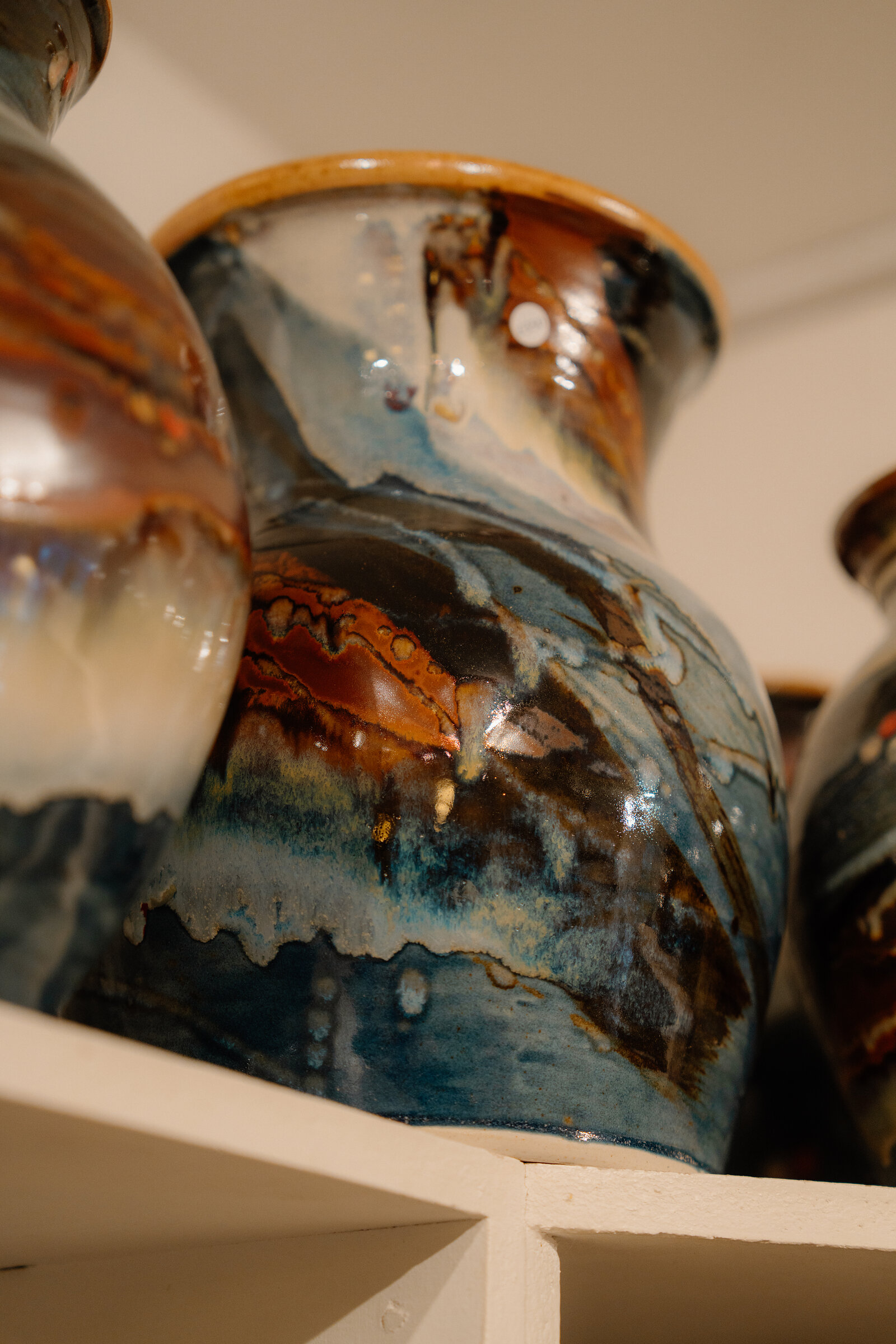 A large glazed vase with swirling blue and amber patterns stands on a shelf at Edinbane Pottery.