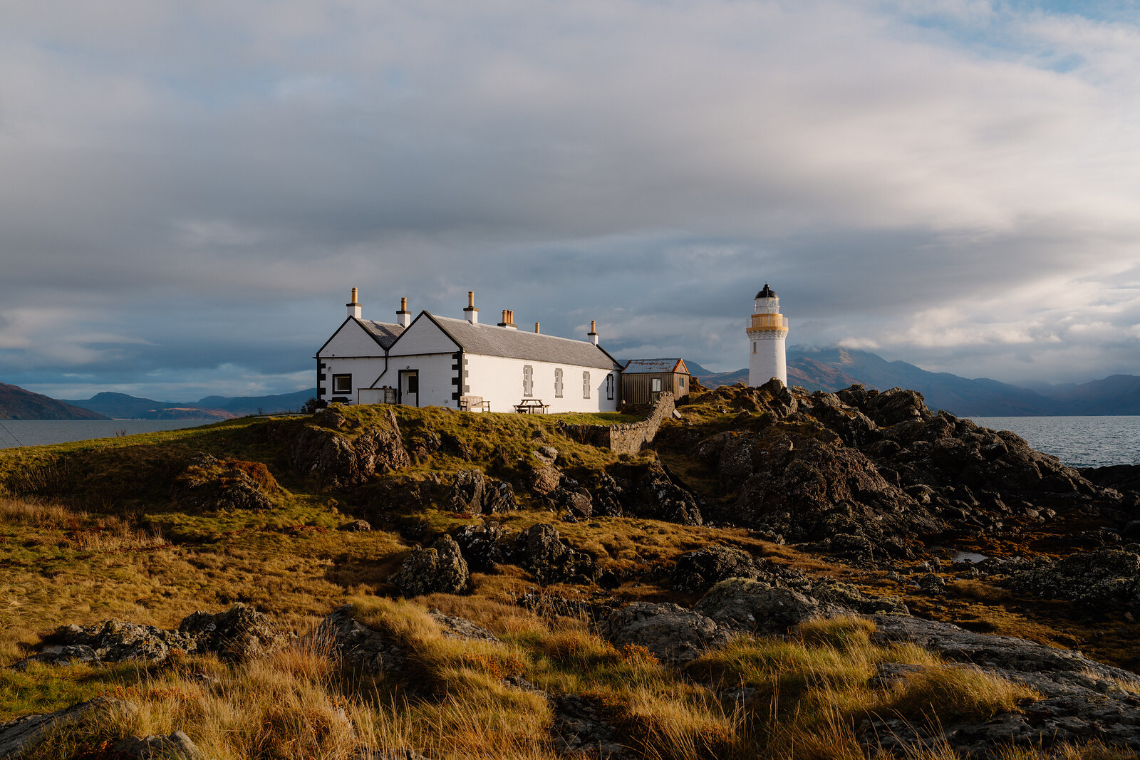 A keeper's cottage and lighthouse stand together on a rocky headland overlooking the sea at Eilean Sionnach.