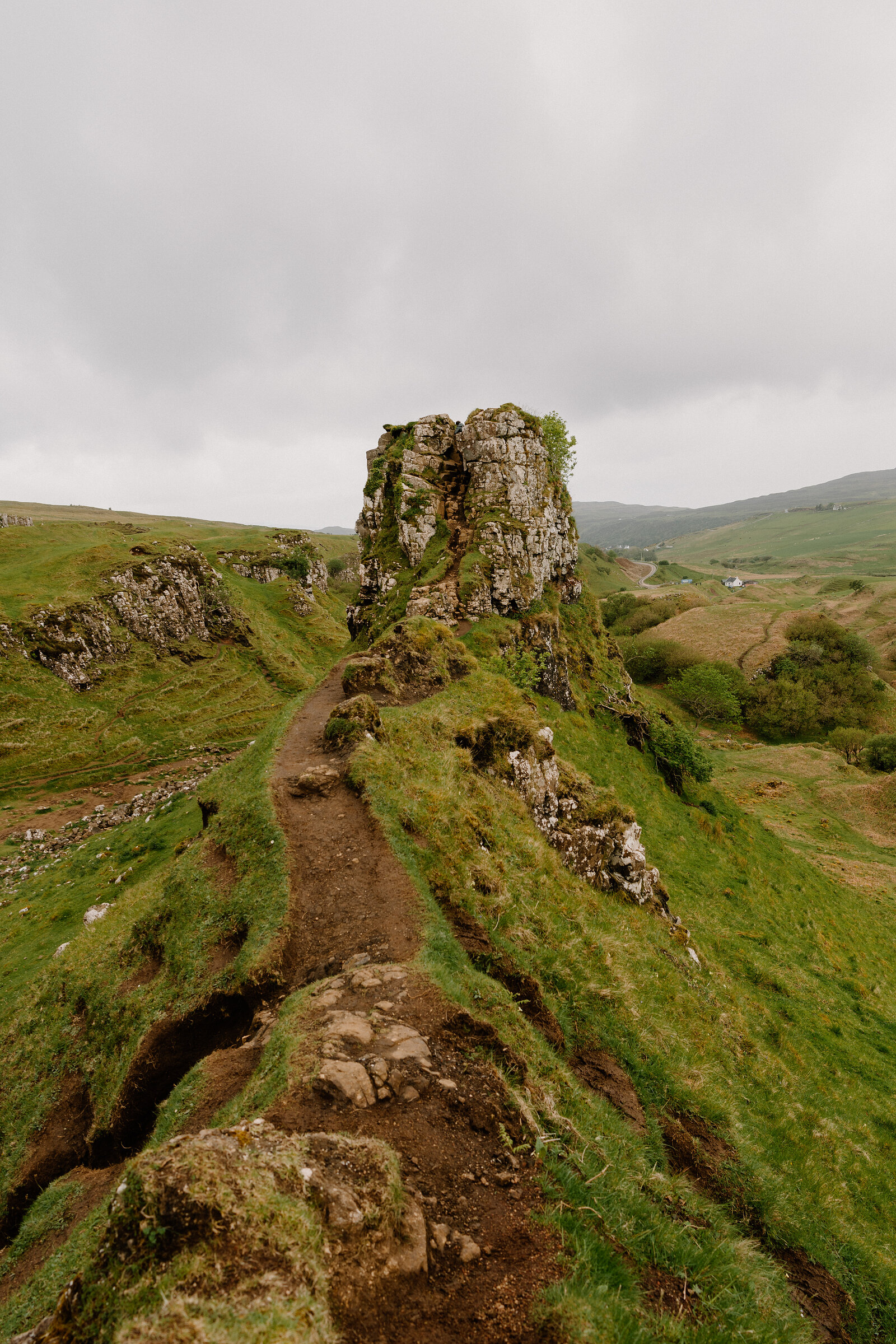 A path leads along a ridge to the rocky outcrop of Castle Ewen in the Fairy Glen, Isle of Skye.