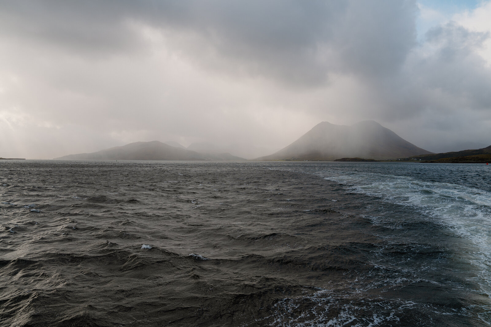 Misty mountains rise beyond the choppy wake of a ferry near the Isle of Skye.