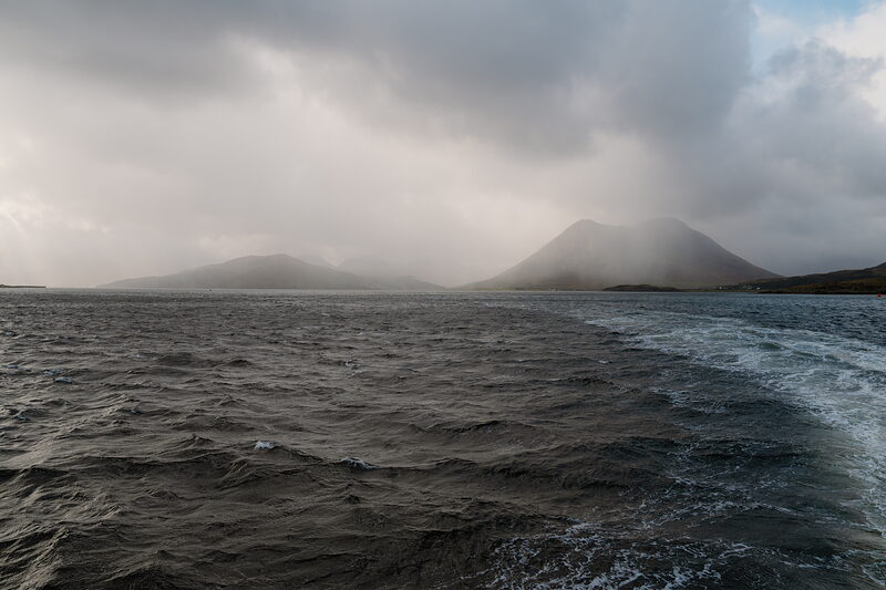 Misty mountains rise beyond the choppy wake of a ferry near the Isle of Skye.