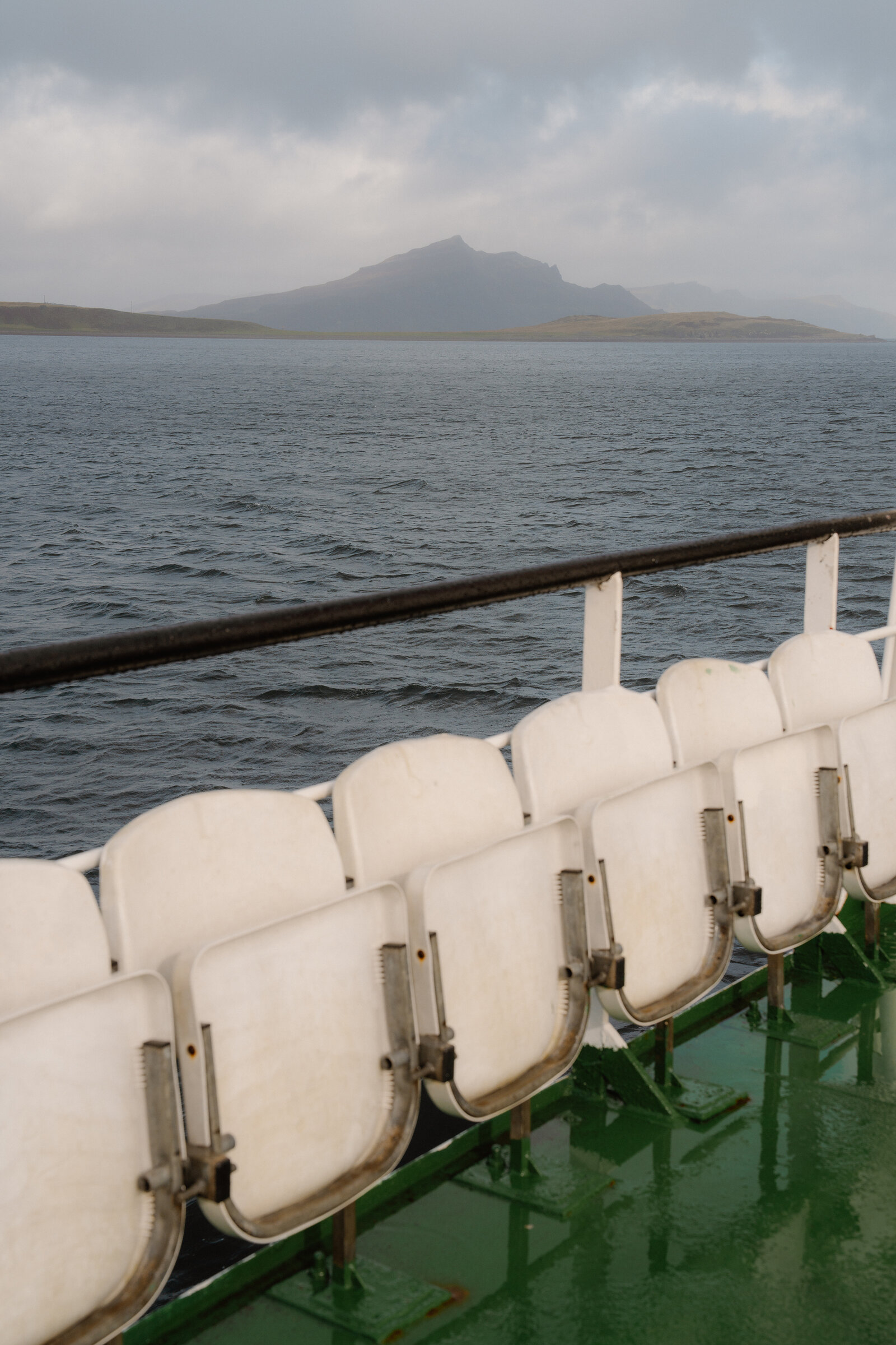 Folded ferry seating faces a misty mountain island near the Isle of Skye.
