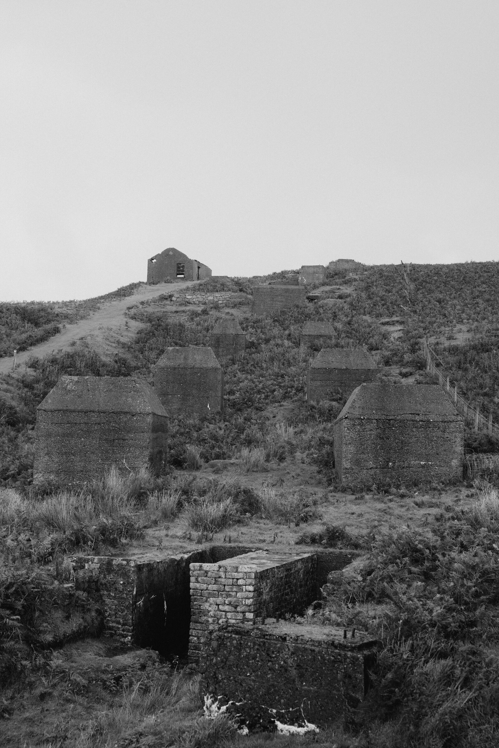 Concrete kiln structures dot a hillside above scattered industrial ruins on the Isle of Skye.