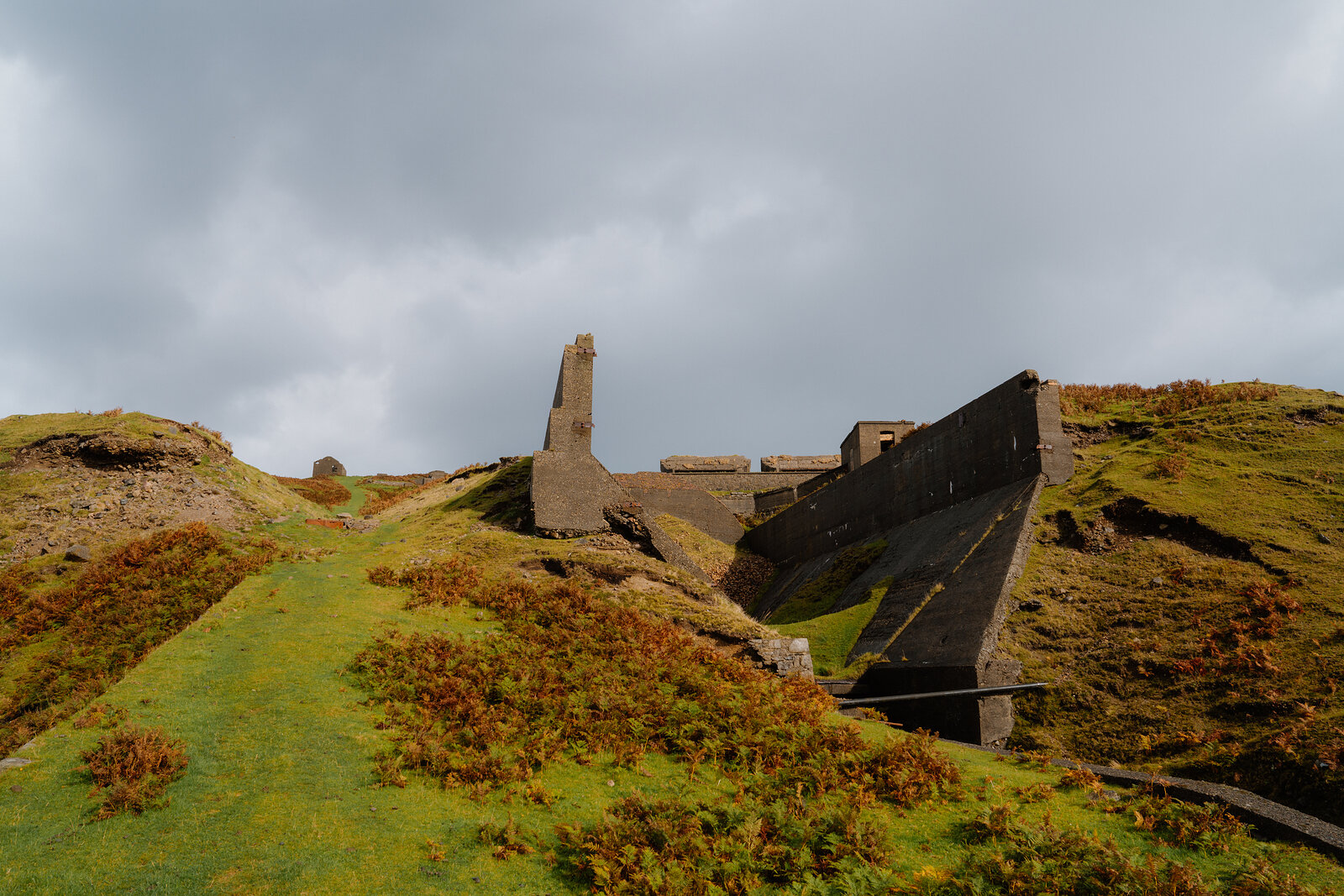 Angular concrete chutes and ruined buildings stand on a grassy hillside on the Isle of Skye.