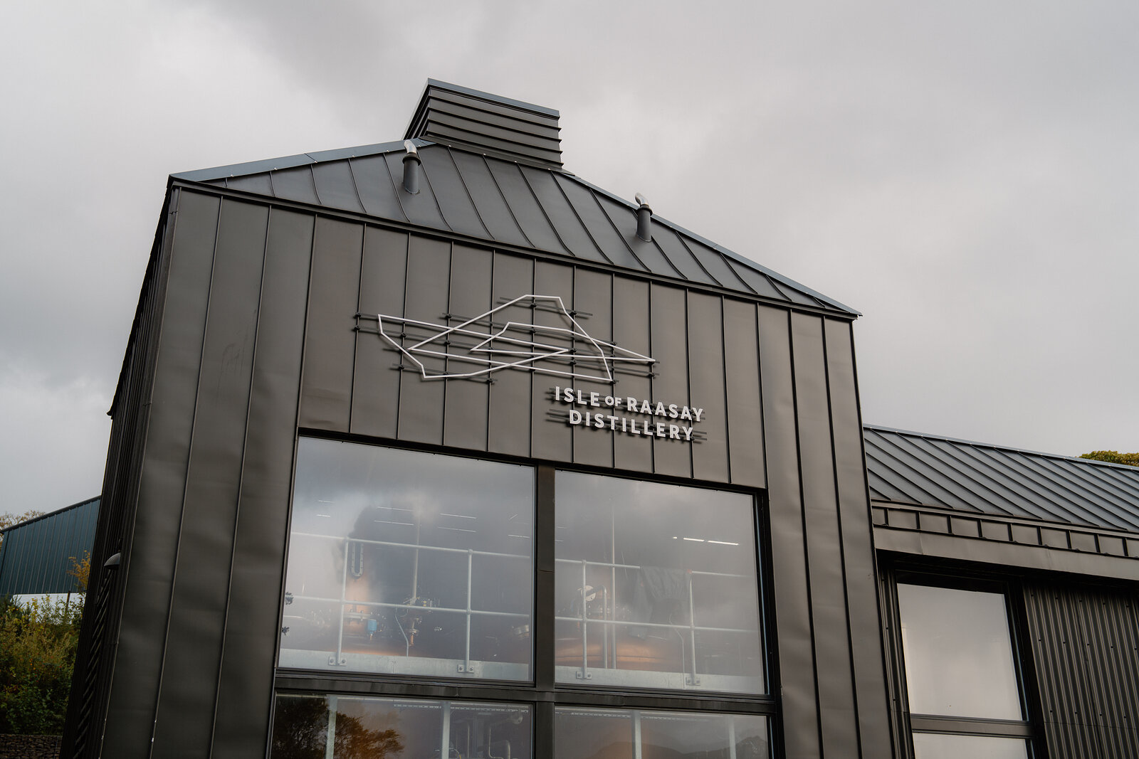 A sign for the Isle of Raasay Distillery marks its dark-clad modern building.